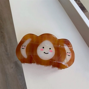 Détail d'une grande pince à cheveux ambre avec des motifs de smiley mignons