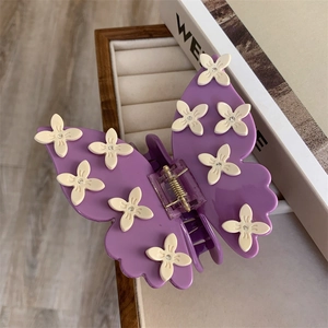 Détail d'une pince à cheveux papillon violette avec petites fleurs blanches et cristaux