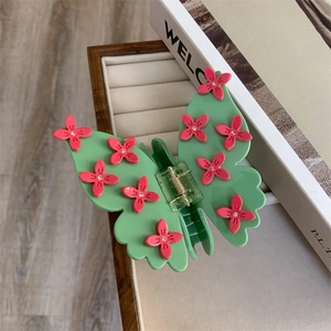 Détail de la pince à cheveux papillon en acétate vert menthe à fleurs roses