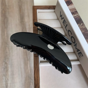 Détail d'une grande pince à cheveux noire en acétate avec finition brillante et rayures