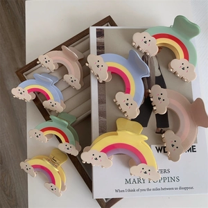 Détail de pinces à cheveux arc-en-ciel avec des décorations de nuages souriants