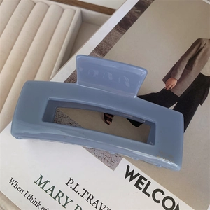 Detail of a rectangle light blue hair claw clip with golden metal accents on a magazine