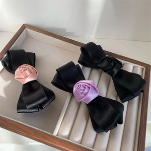 Detailed view of handmade rose ribbon hair clips in black, pink and purple silk