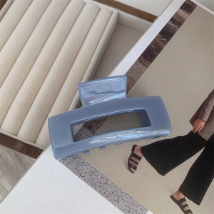 Detail of blue acetate hair claw with gold logo lettering on a fashion magazine