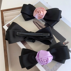 Detail of elegant black ribbon bow hair clips with satin rose and metal duckbill clip