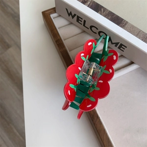 Close-up of strawberry-shaped acrylic hair claw clip with red body and green leaves