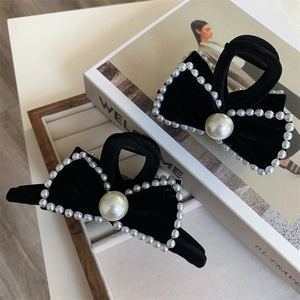 Detail of elegant black velvet bow hair clips with white pearl trim for hair styling