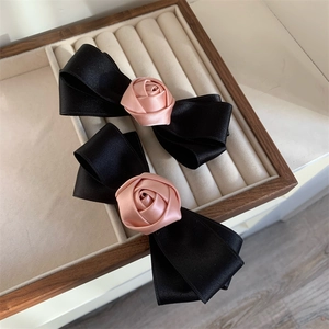 Close-up of pink satin rose and black double-layered ribbon bow hair clip in display box