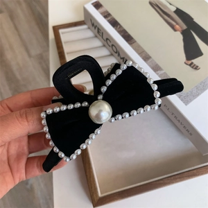 Detail of a black velvet bow hair claw clip decorated with elegant white pearls