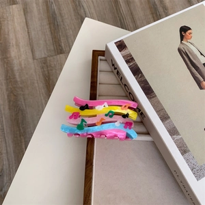 Detailed shot of colorful note patterned acrylic hair claws on a wooden display tray