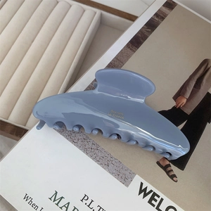 Detail of blue acetate hair claw clip with gold lettering on a stylish background