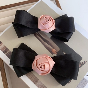 Detail of two-piece set bow hair clips with pink satin roses and black grosgrain ribbon