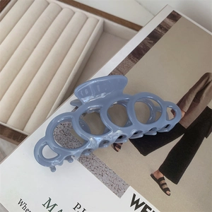 Detail of a large matte blue acetate hair claw clip with a hollow circular link design