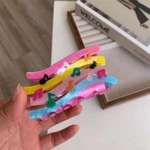Detail shot of four colorful music note hair claws in yellow, pink and blue finish