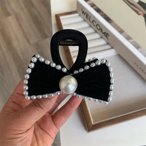 Detail of velvet bow hair claw with elegant pearl embellishments and metal spring
