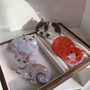 Détail de quatre pinces à cheveux chat en acrylique aux couleurs marbrées sur bois