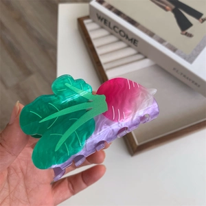 Detail shot of a vegetable radish-shaped hair claw clip with green leaves and pink marble texture