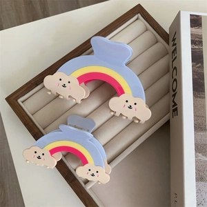 Détail de deux pinces à cheveux arc-en-ciel dans une boîte à bijoux rayée