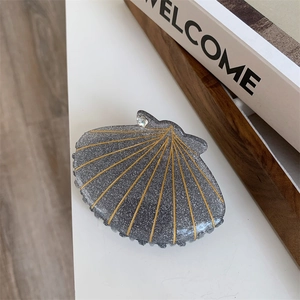 Detail of gray shell hair claw clip with golden glitter lines and rhinestone accent