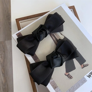 Close-up of black satin bow hair clips with rose detail on a fashion magazine