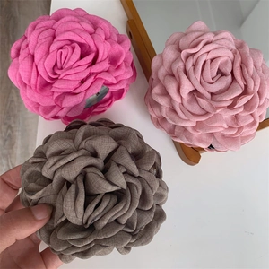 Close-up of three handmade fabric rose hair claws in pink and brown with ruffled petals