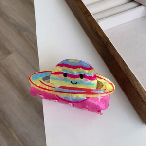 Detailed macro view of a colorful planet-shaped acrylic hair claw clip with smiling face