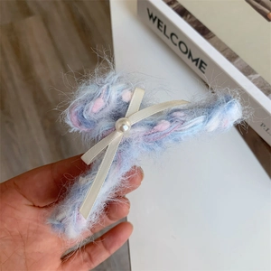 Detail van de pluche haarklem met blauw-roze garenstrik en een centrale parelversiering