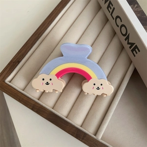 Détail macro d'une pince à cheveux arc-en-ciel avec nuages souriants sur velours