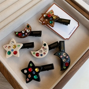 Gros plan de barrettes étoile et lune serties de strass sur un plateau à bijoux en velours
