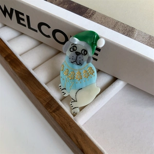 Close-up of a Christmas pug brooch in a green hat and blue sweater on a beige stand