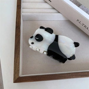 Macro detail of a panda-shaped acetate hair claw clip with pearlescent white finish