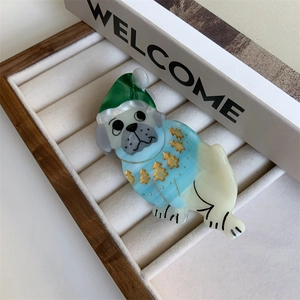 Detail of cute Pug dog acetate hair clip with green Christmas hat and blue sweater
