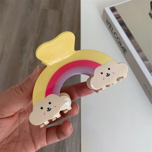 Détail de la pince à cheveux arc-en-ciel avec de mignons nuages souriants colorés
