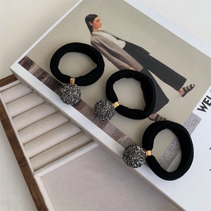 Detailed macro view of three high-elasticity black hair ties with crystal-encrusted spheres