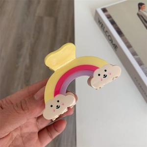 Vue détaillée d'une pince à cheveux arc-en-ciel avec des nuages souriants sur un bureau