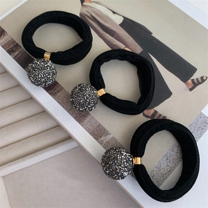 Close-up of three black elastic hair ties with grey rhinestone spheres on a jewelry tray