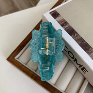 Close-up of a sparkling sea-green butterfly hair claw clip with a glossy glitter finish