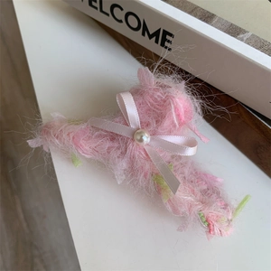 Detail van de roze pluche haarklem met een zijden strik en een centrale parel