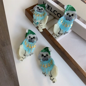 Detail of pug-shaped acetate hair claw clips with festive sweater and marble patterns