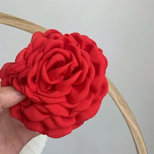 Detail of red fabric rose hair claw showing layered petal texture and linen material