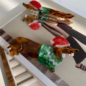 Detail view of acetate dachshund hair claw with festive Christmas hat and green sweater