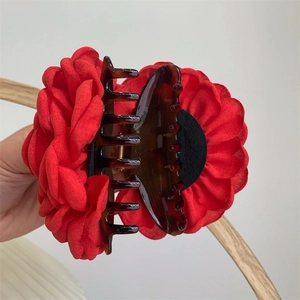 Close-up of red fabric rose flower hair claw clip with amber resin shark hair accessory