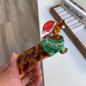 Detail of Christmas dachshund hair claw clip with red hat and green sweater patterns