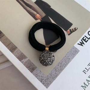 Detail of high-elasticity hair tie with a sparkling crystal ball pendant on a magazine