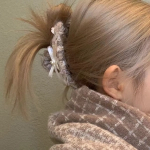 Elegante bruine haarklem met witte strik en parel gedragen in een paardenstaart