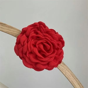 Detailed close-up of a large red fabric rose hair claw clip with chiffon layered petals