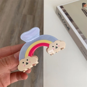Détail macro d'une pince à cheveux arc-en-ciel avec des motifs de nuages souriants mignons