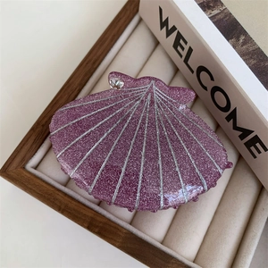 Purple shell hair claw clip with silver accents and sparkling glitter in a jewelry tray