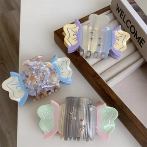 Detailed view of candy-shaped acetate hair claws with sparkling rhinestones in pastel hues