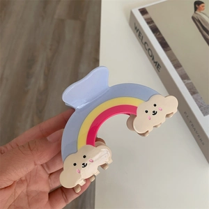 Détail d'une pince à cheveux arc-en-ciel avec des motifs d'ours nuages et des rayures
